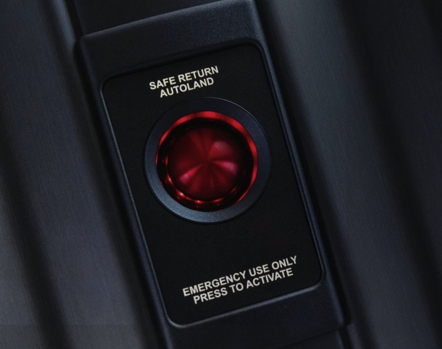 Illuminated red Safe Return Autoland button in the Cirrus cabin ceiling, labeled Emergency use only, press to activate